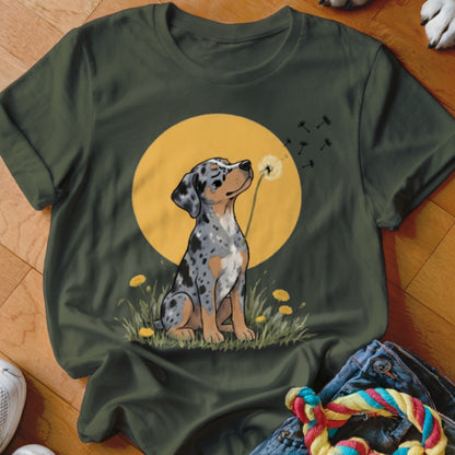 Olive green t-shirt featuring an illustration of a merle puppy blowing a dandelion against a yellow moon.
