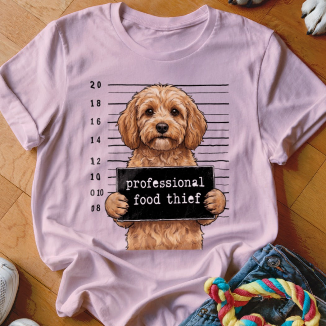 Light pink t-shirt with a cartoon dog holding a sign that says "professional food thief."