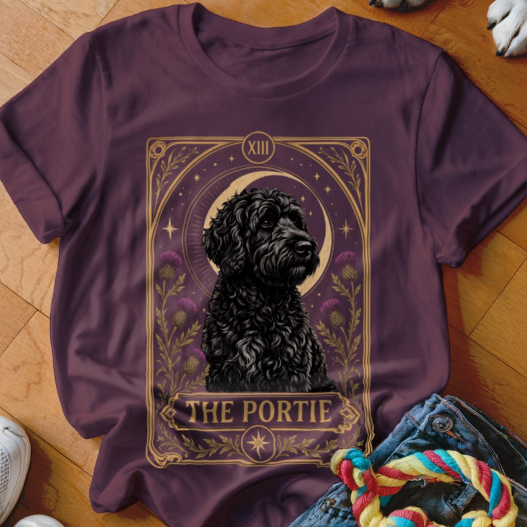 Dark plum t-shirt featuring a tarot-style graphic of a black dog and the text The Portie.