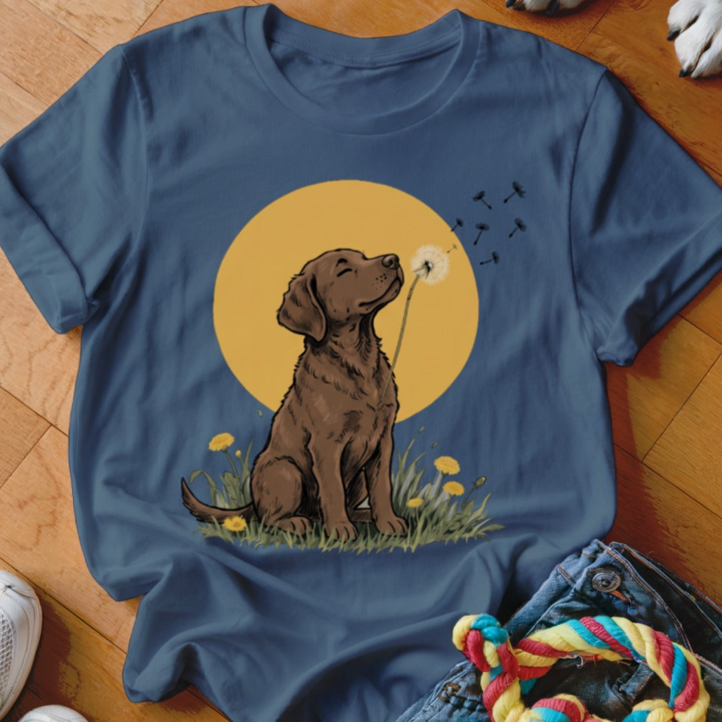Dark blue t-shirt featuring a graphic of a brown dog blowing dandelion seeds against a yellow circle background.