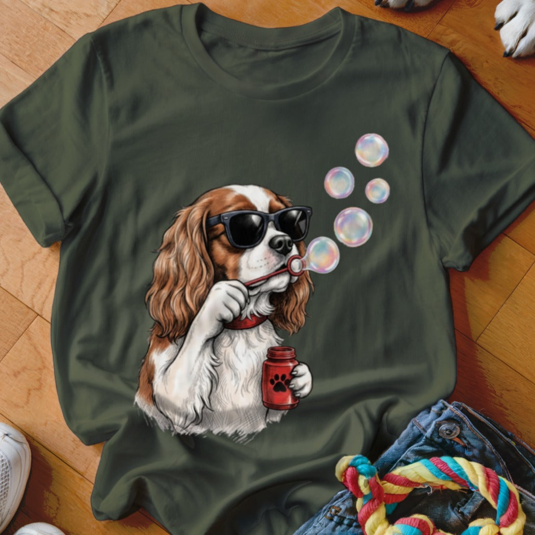 Dark green t-shirt featuring a graphic of a Cavalier King Charles Spaniel wearing sunglasses and blowing bubbles.
