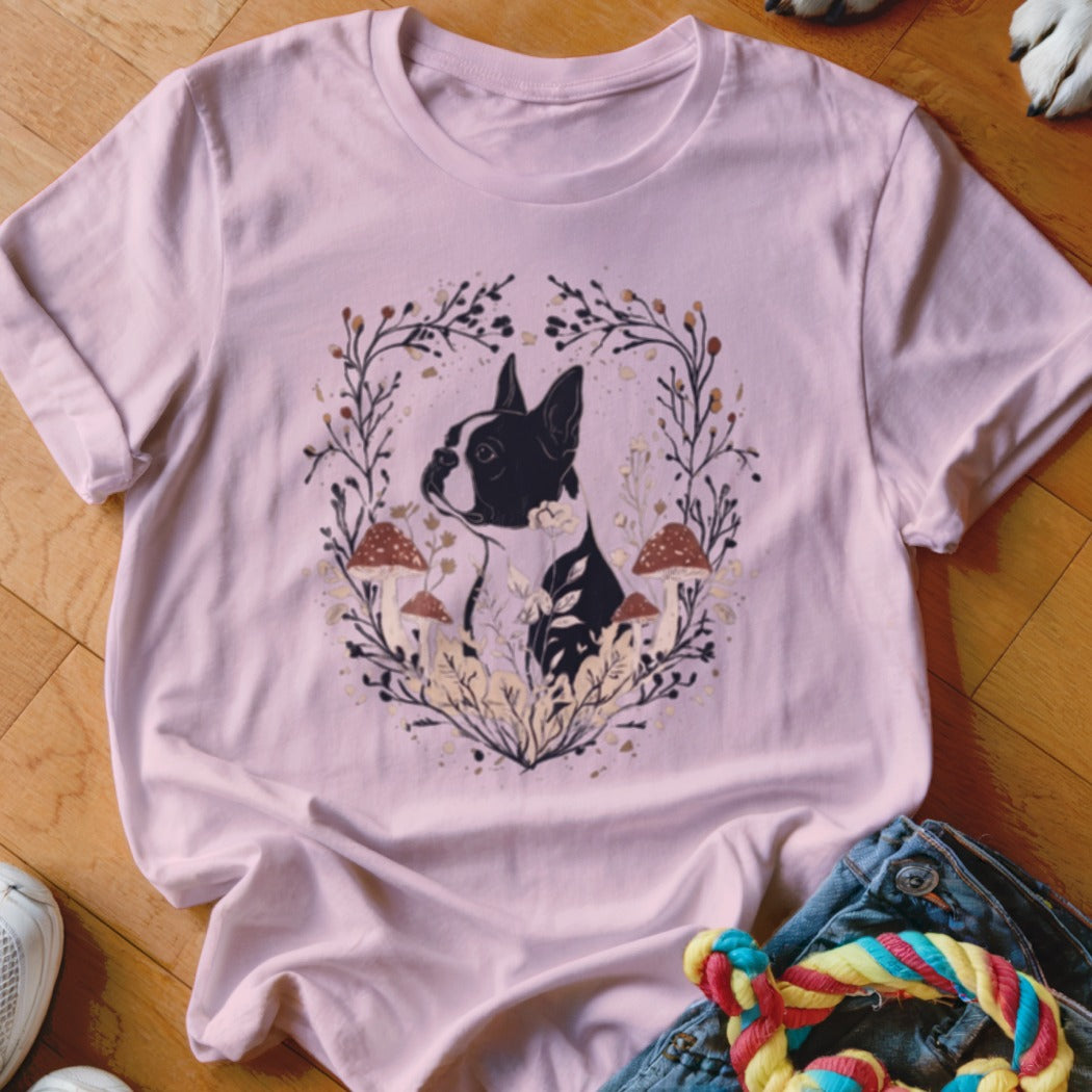 A light pink t-shirt features a graphic of a Boston terrier surrounded by mushrooms and foliage.