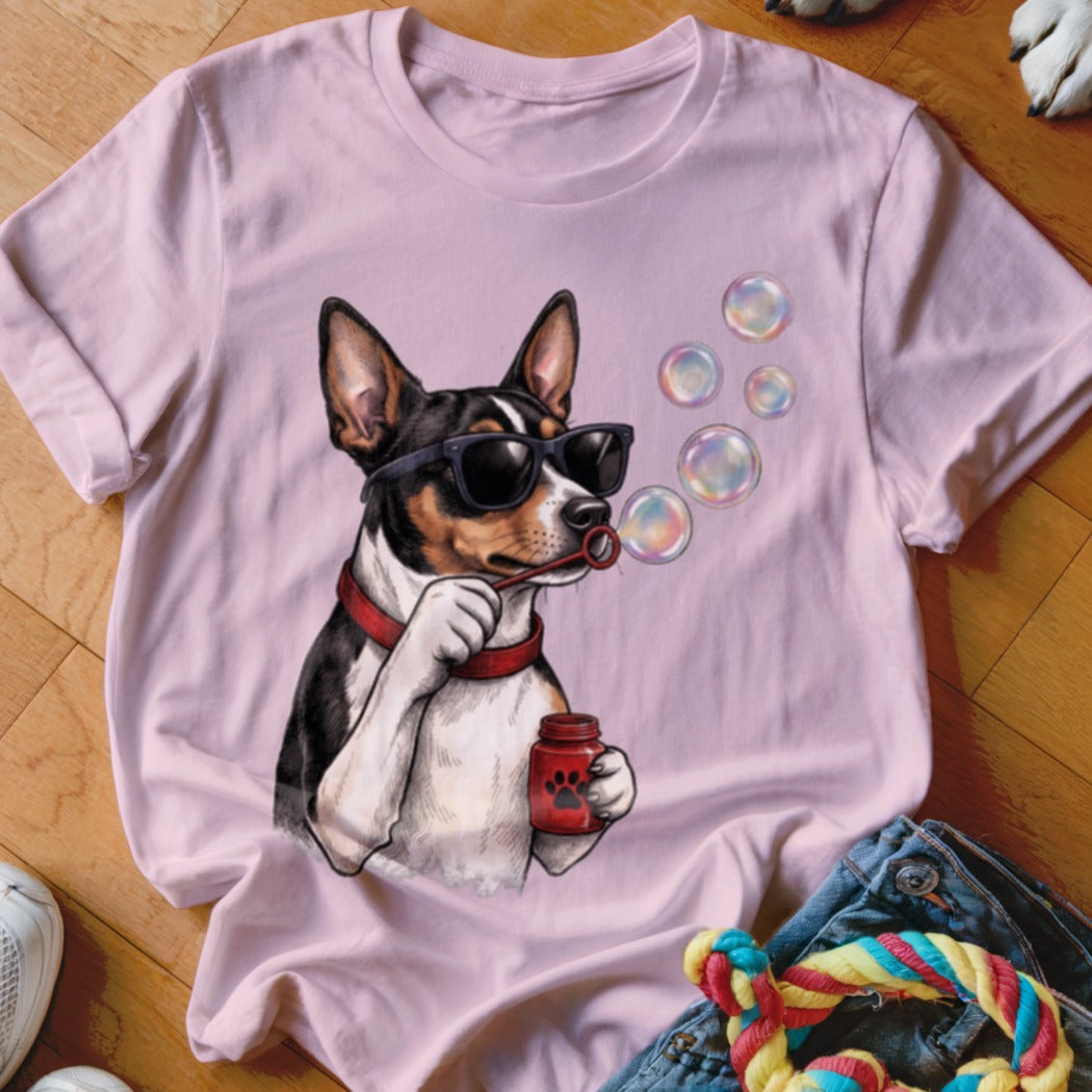 A light pink crewneck t-shirt featuring a graphic of a black and white dog wearing sunglasses and blowing bubbles.