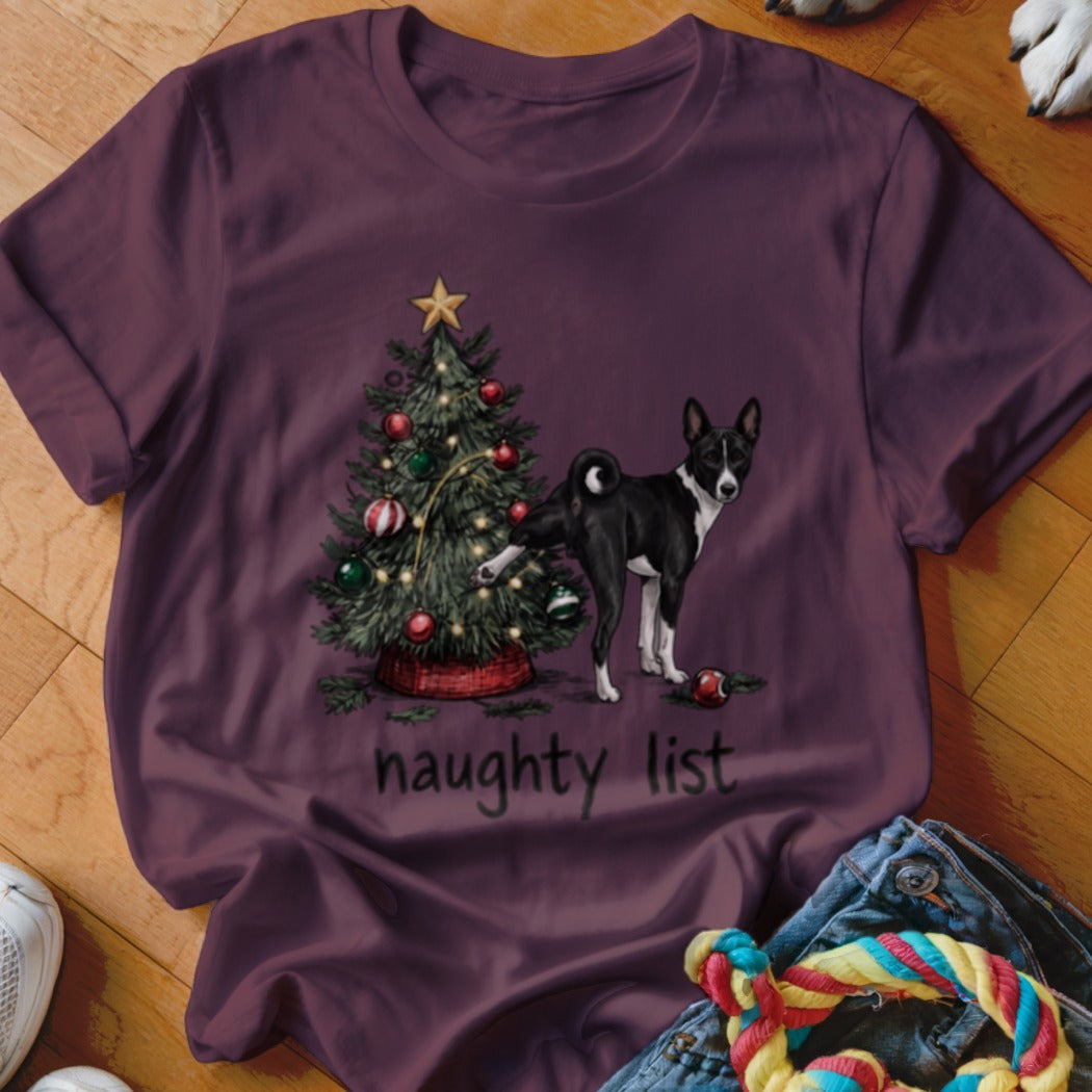 Maroon t-shirt featuring a graphic of a dog lifting its leg by a Christmas tree with the text naughty list.