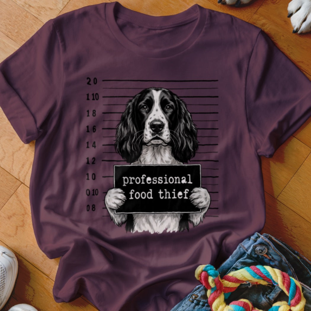 English Springer Spaniel mugshot with "professional food thief" sign on a t-shirt.