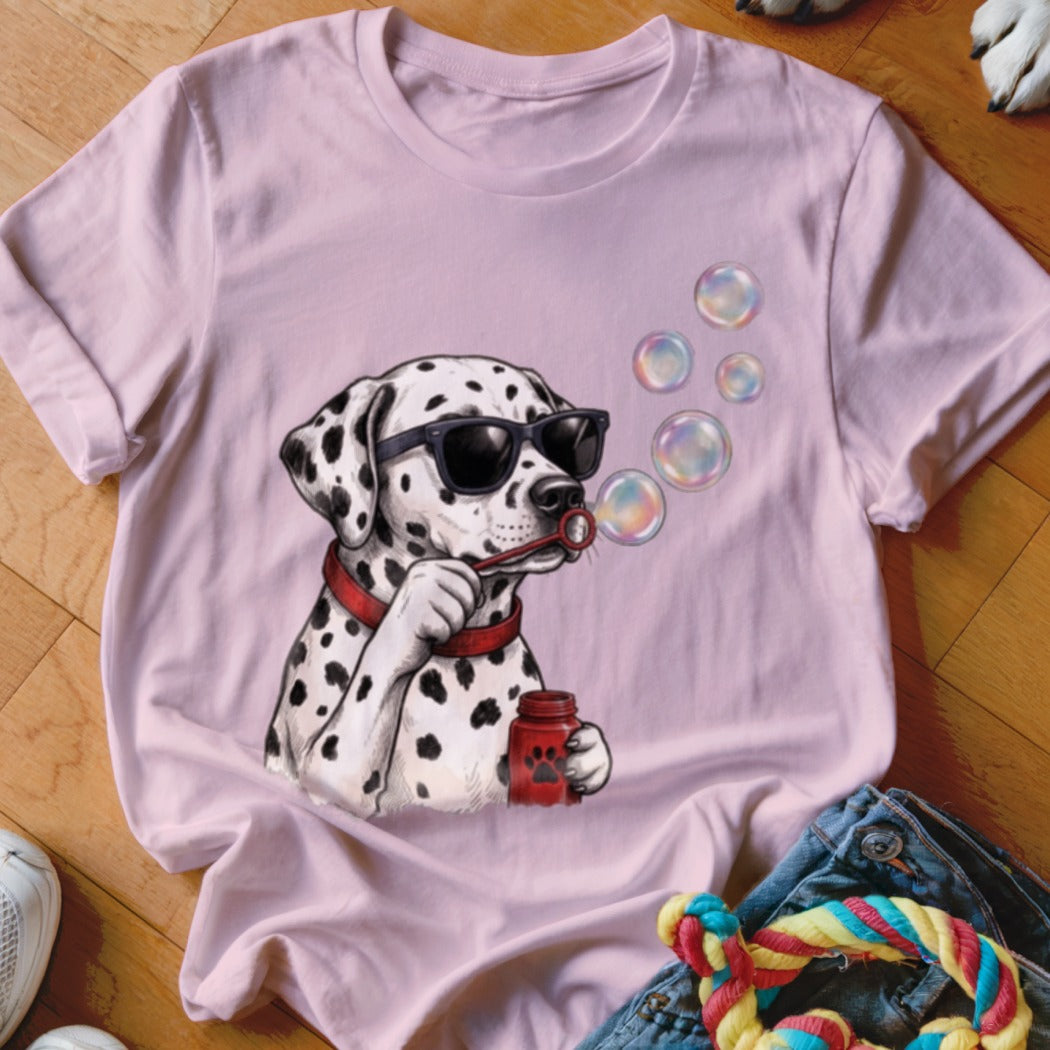 A light pink t-shirt featuring a graphic of a Dalmatian wearing sunglasses and blowing soap bubbles.