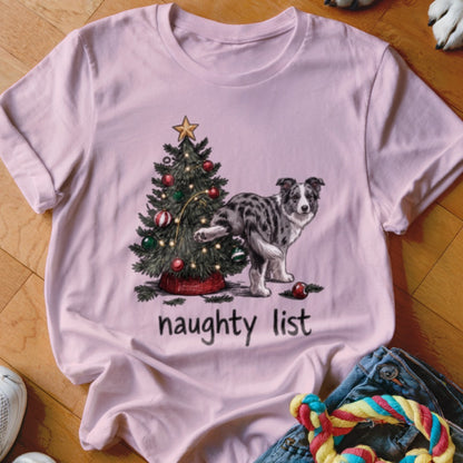 A pink t-shirt with a graphic of an Australian Shepherd peeing on a Christmas tree, with the text "naughty list".