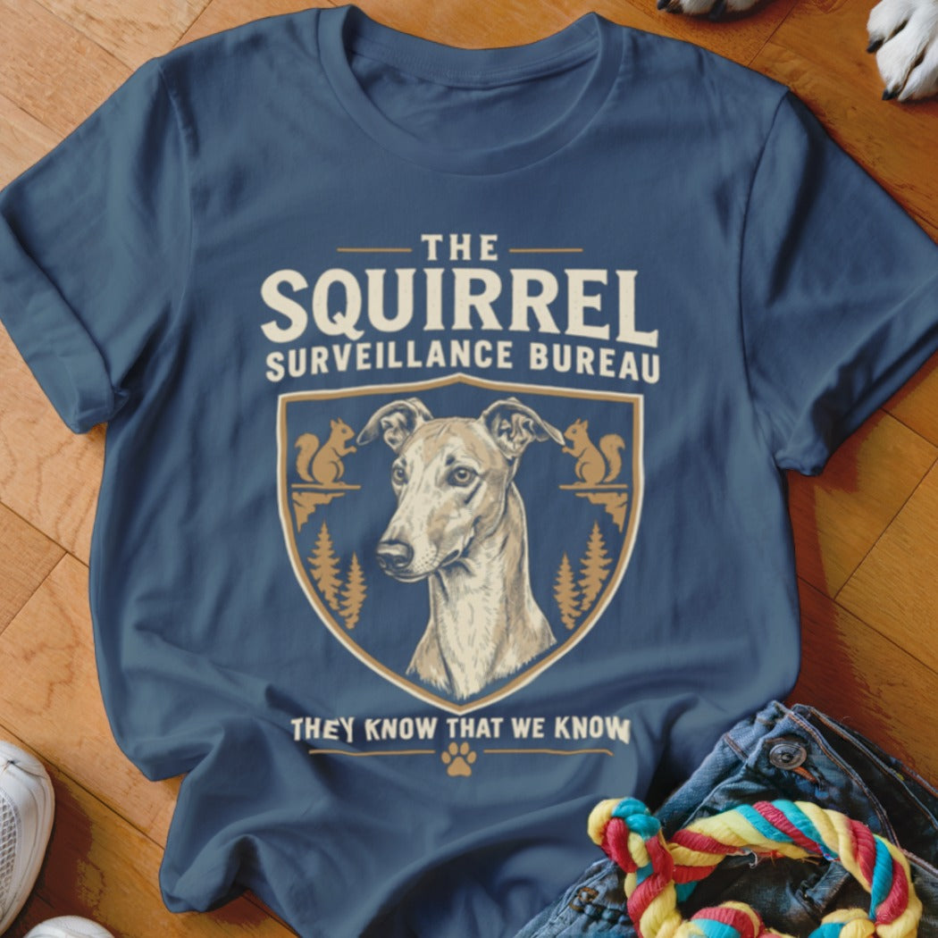 Dark blue t-shirt featuring a crest with a greyhound, squirrels, trees, and text reading The Squirrel Surveillance Bureau.