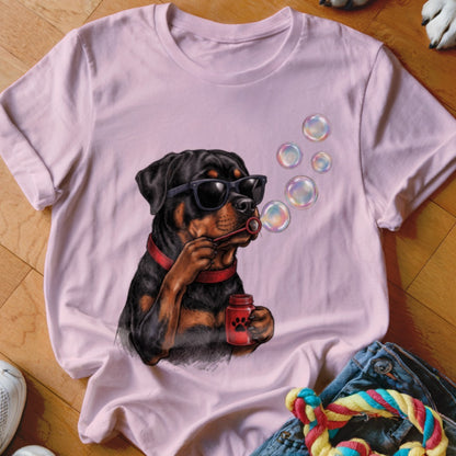 A light pink t-shirt featuring a graphic of a Rottweiler wearing sunglasses and blowing soap bubbles.