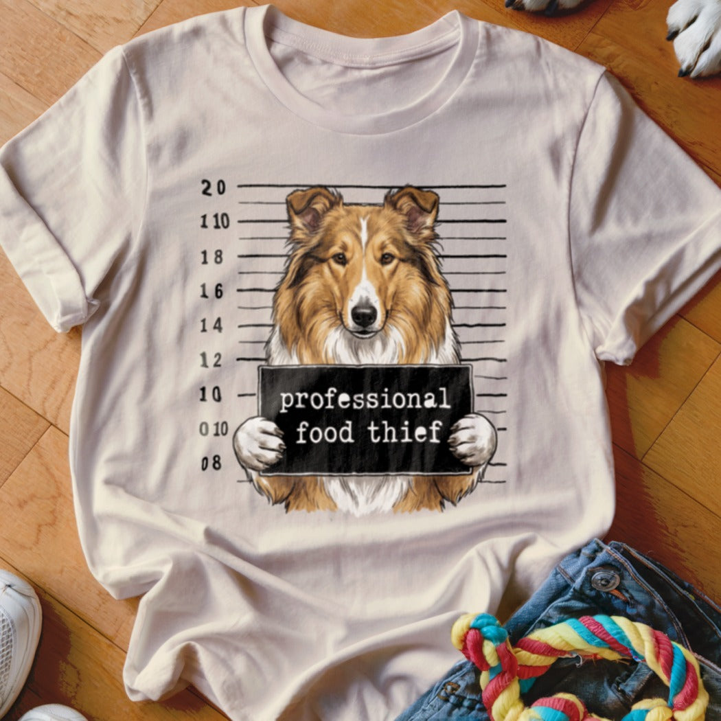 Collie dog mugshot holding sign that reads "professional food thief".