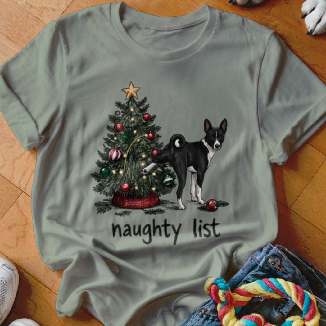 Sage green t-shirt with a graphic of a dog lifting its leg on a Christmas tree and the text "naughty list".