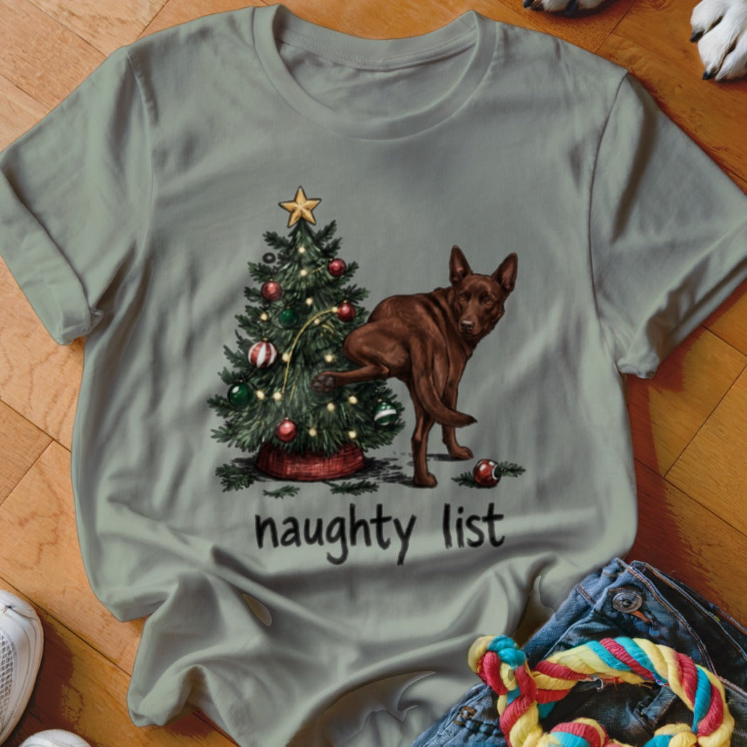 Brown dog with leg raised at decorated Christmas tree with text "naughty list".