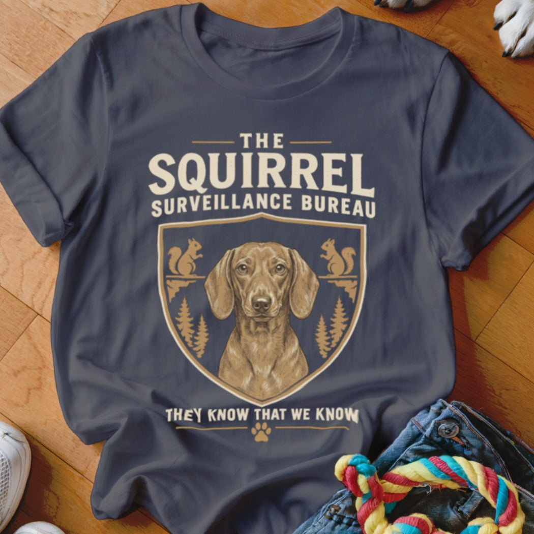 A dark gray t-shirt featuring a dachshund graphic and text reading The Squirrel Surveillance Bureau.