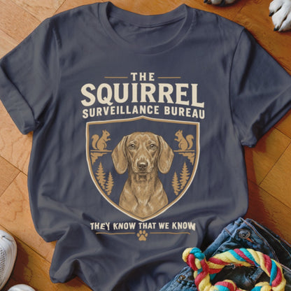A dark gray t-shirt featuring a dachshund graphic and text reading The Squirrel Surveillance Bureau.