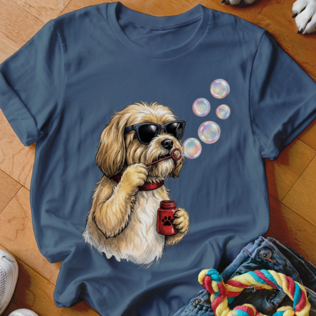 A blue t-shirt featuring an illustration of a fluffy blonde dog wearing sunglasses and blowing bubbles.