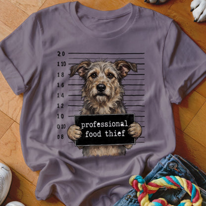Terrier dog mugshot with "professional food thief" sign on a purple t-shirt.
