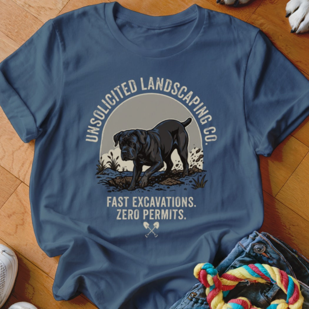 Blue t-shirt with black dog digging. Text: "UNSOLICITED LANDSCAPING CO. FAST EXCAVATIONS. ZERO PERMITS."