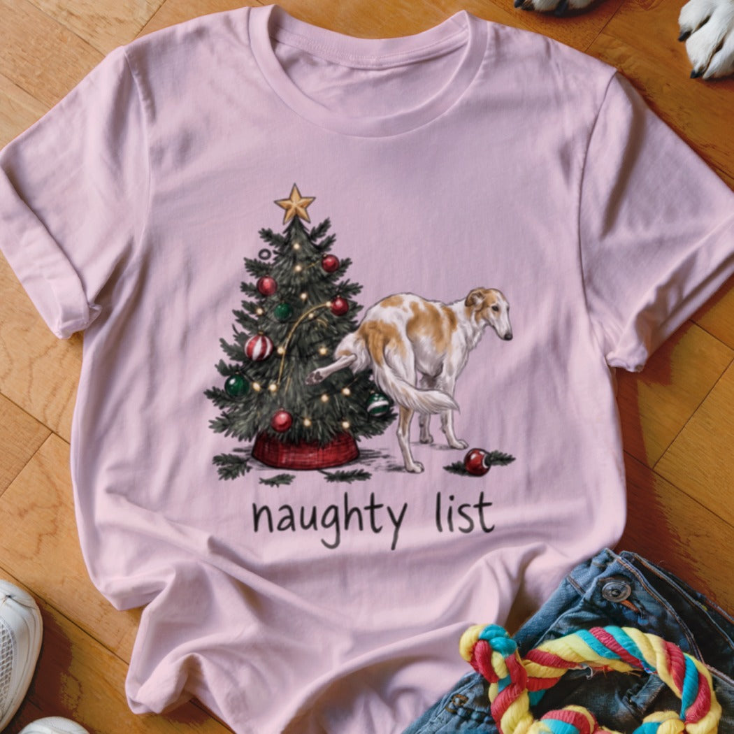 Light pink t-shirt featuring a Borzoi dog lifting its leg on a Christmas tree with the text naughty list.