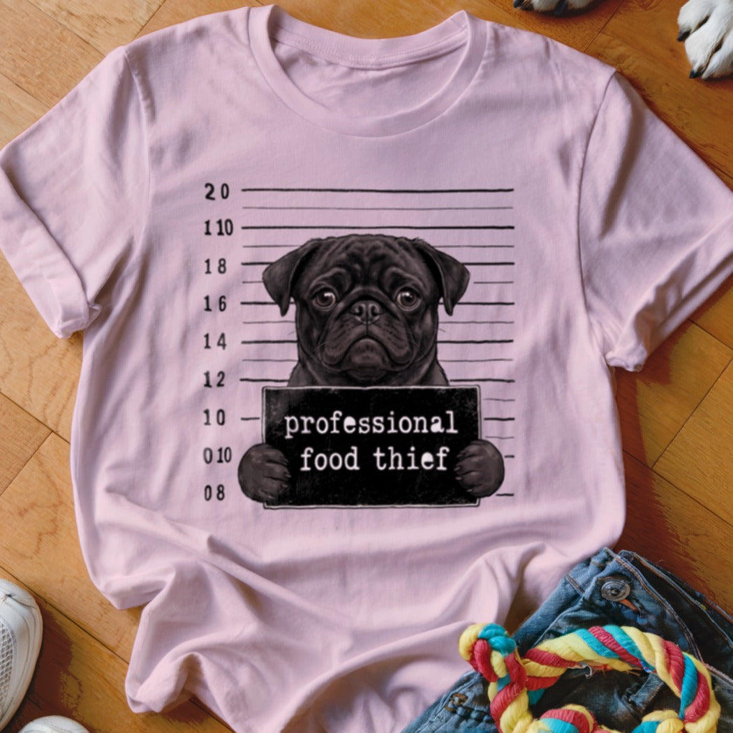 Pink t-shirt with a black pug in a mugshot holding a sign saying "professional food thief".