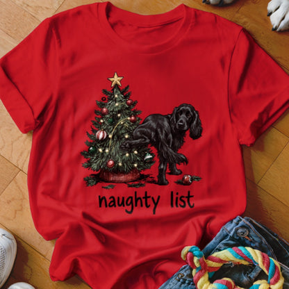 Black dog next to Christmas tree with text "naughty list" on red shirt.