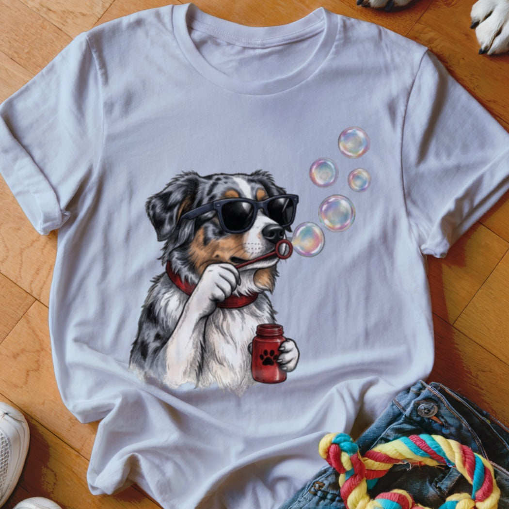 A white crewneck t-shirt featuring a graphic of an Australian Shepherd wearing sunglasses and blowing bubbles.