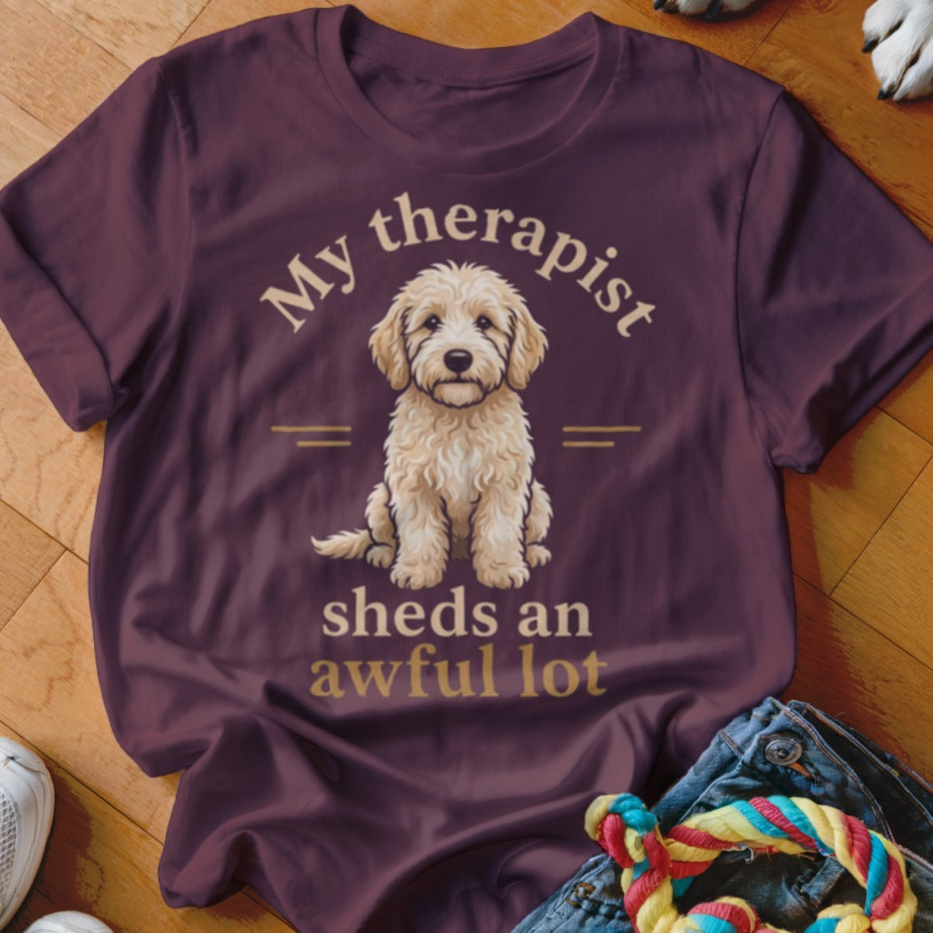 Maroon t-shirt with gold text "My therapist sheds an awful lot" and dog illustration.