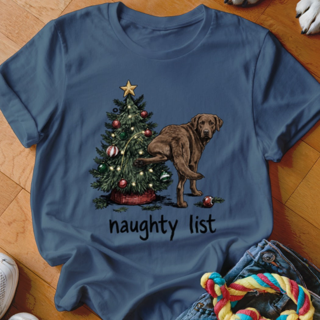 Brown dog lifting leg near Christmas tree with text "naughty list".