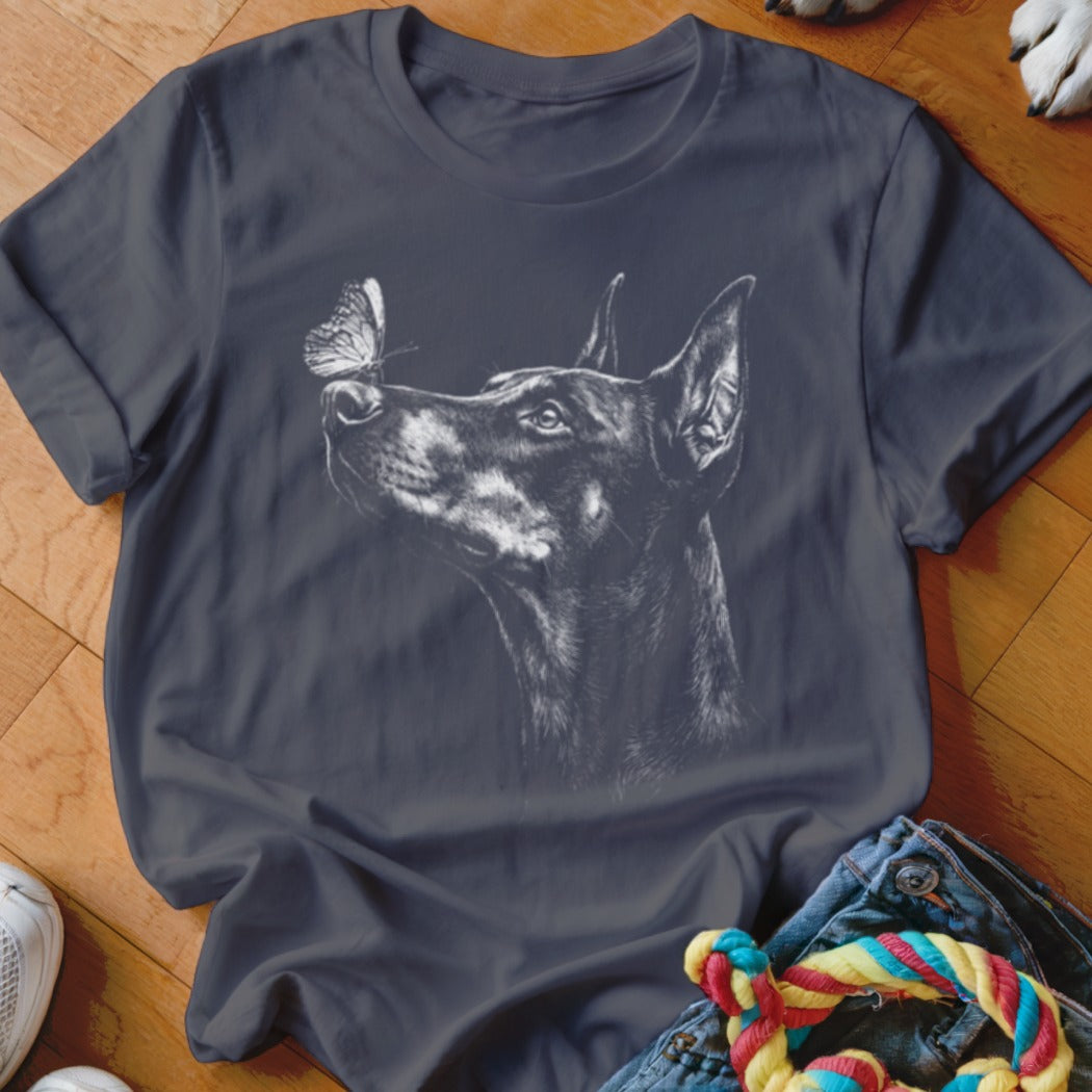 A dark gray t-shirt featuring a white sketch of a Doberman looking at a butterfly.