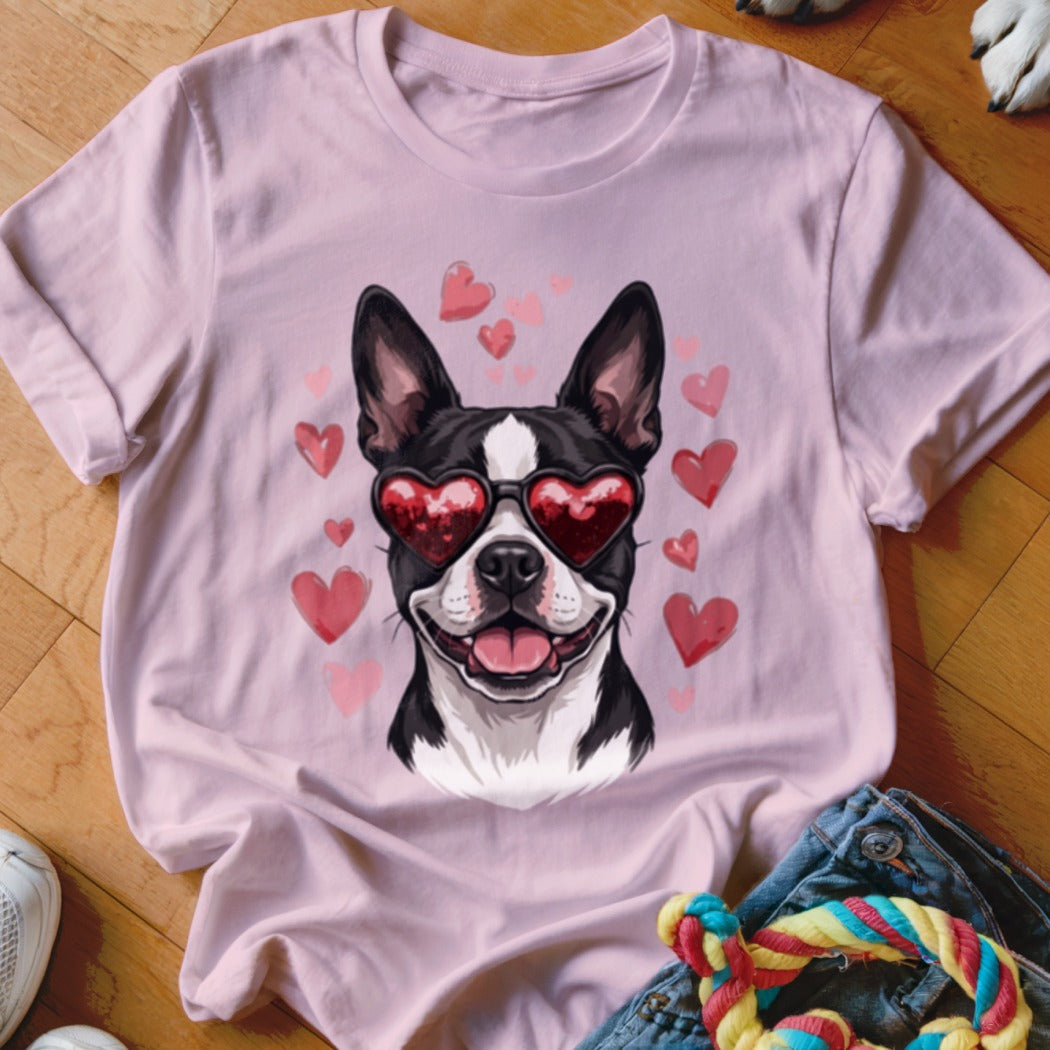 A light pink t-shirt features a graphic of a Boston Terrier wearing heart-shaped sunglasses surrounded by floating pink hearts.