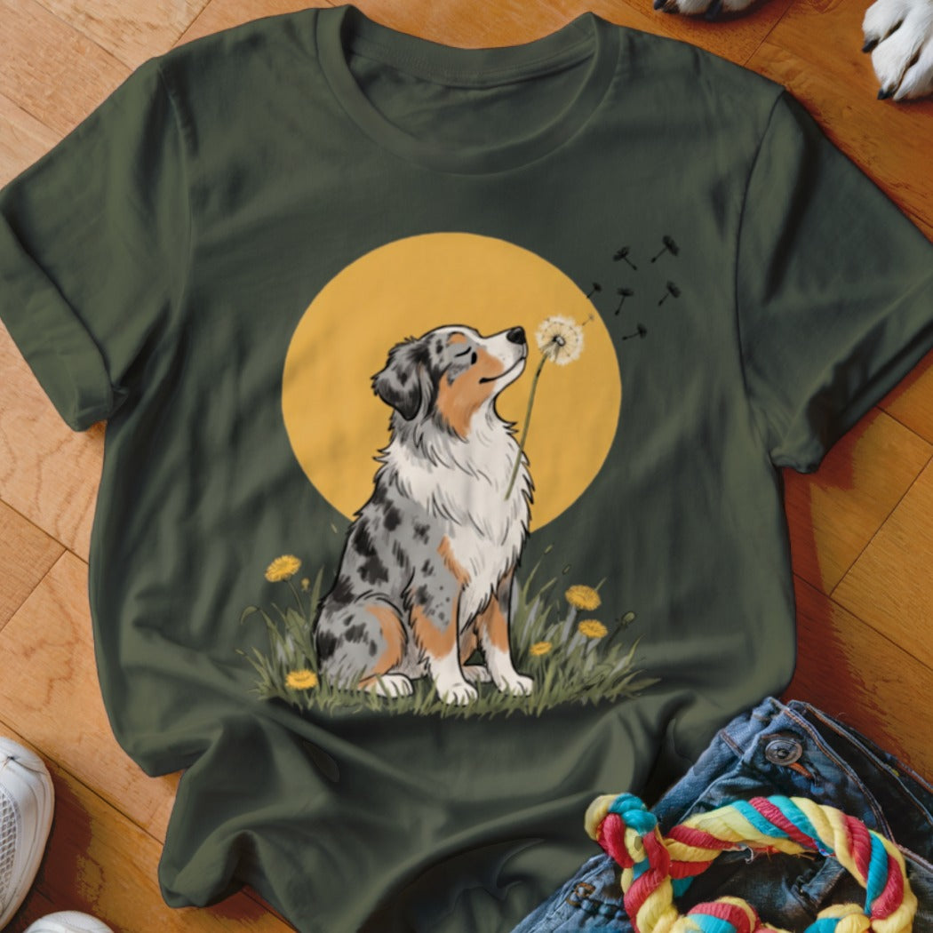 Dark green t-shirt featuring an illustrated Australian Shepherd dog blowing a dandelion against a yellow sun.