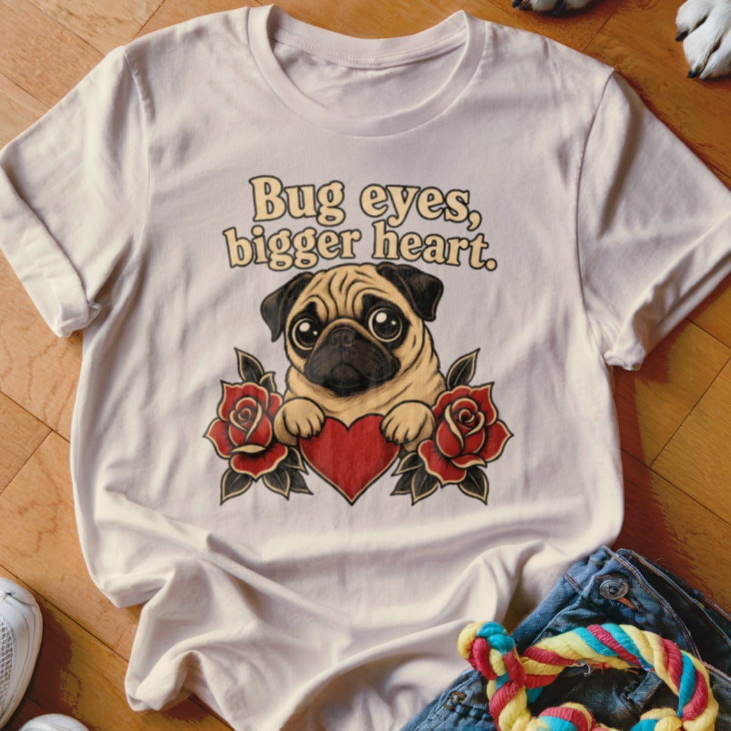 White t-shirt with a pug holding a heart, surrounded by roses, and text "Bug eyes, bigger heart."