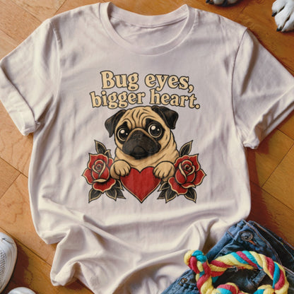 White t-shirt with a pug holding a heart, surrounded by roses, and text "Bug eyes, bigger heart."