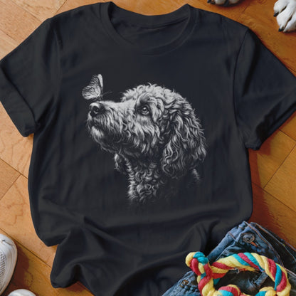 Black crewneck t-shirt featuring a sketch of a poodle looking at a butterfly on its nose.