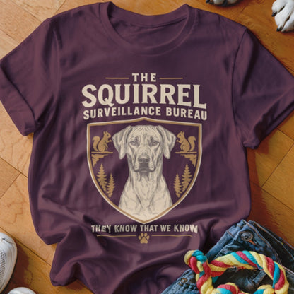 Maroon t-shirt featuring a dog graphic, crest, and text reading The Squirrel Surveillance Bureau.