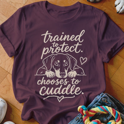 Maroon t-shirt with dog graphic and text "trained to protect. chooses to cuddle."