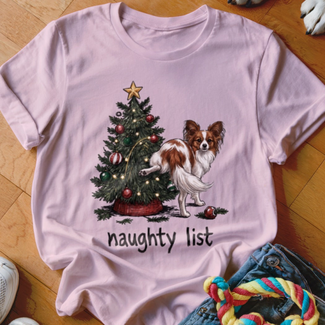 Papillon dog at Christmas tree with "naughty list" text.