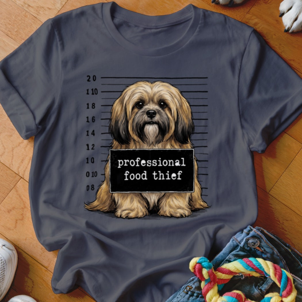 Shih Tzu dog in mugshot with "professional food thief" sign.