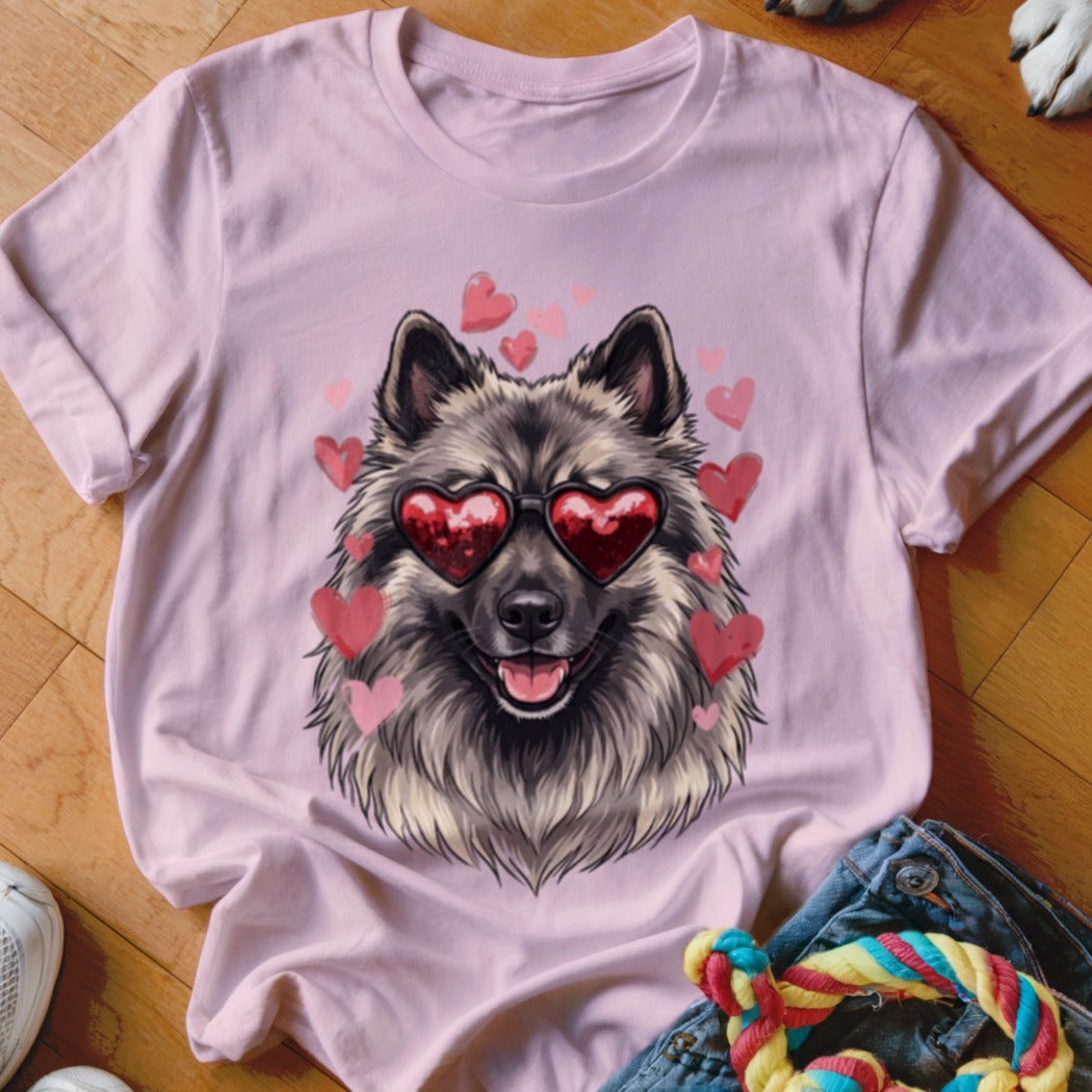 A light pink t-shirt with a graphic of a smiling Keeshond dog wearing heart-shaped sunglasses surrounded by floating pink hearts.