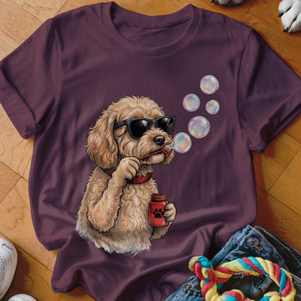 Maroon t-shirt featuring an illustration of a curly-haired dog wearing sunglasses and blowing bubbles.