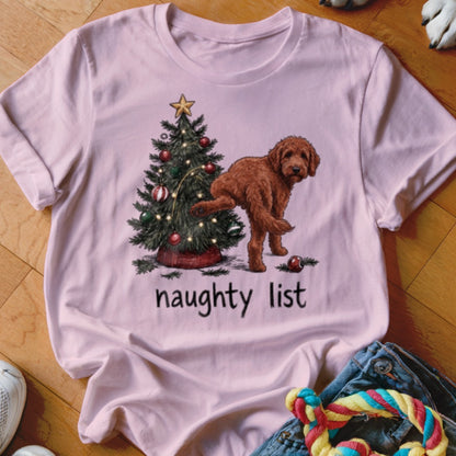 Pink t-shirt with a doodle dog by a Christmas tree, text reads "naughty list".