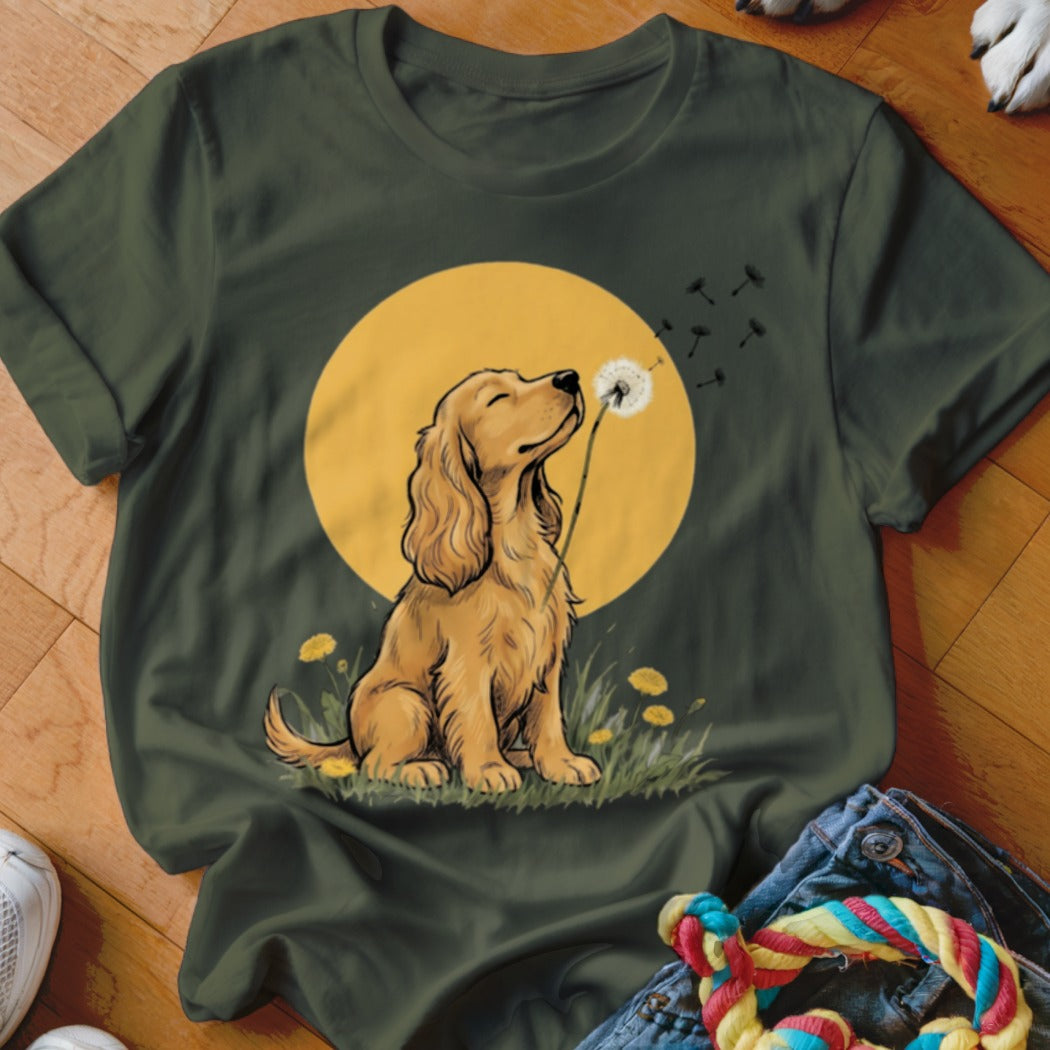 A dark green t-shirt featuring a graphic of a golden dog blowing dandelion seeds.
