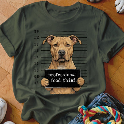 Tan pit bull dog in mugshot holding sign that says "professional food thief".