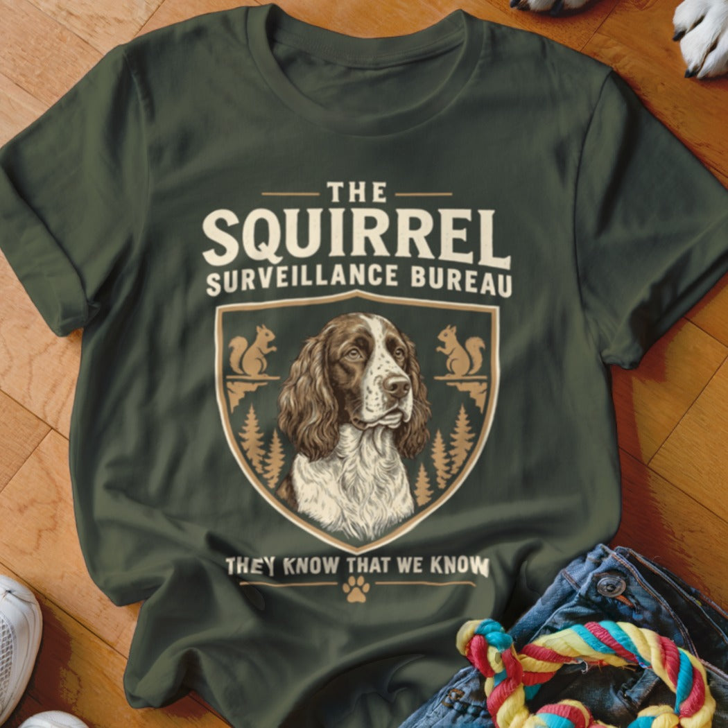 Dark green t-shirt with a vintage-style graphic of a dog inside a crest labeled The Squirrel Surveillance Bureau.