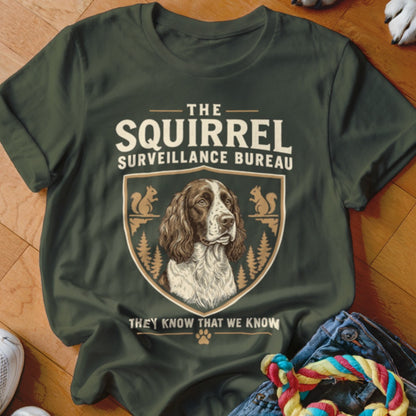 Dark green t-shirt with a vintage-style graphic of a dog inside a crest labeled The Squirrel Surveillance Bureau.