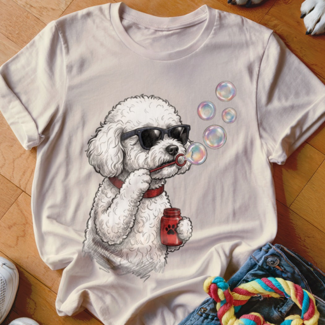 Light-colored t-shirt featuring a cartoon illustration of a fluffy poodle wearing sunglasses and blowing bubbles.