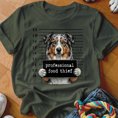 Dog mugshot with sign reading "professional food thief" on a green t-shirt.