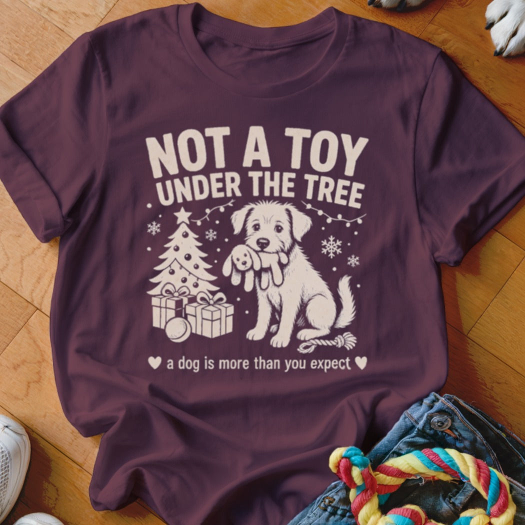Maroon t-shirt with Christmas tree, presents, and dog holding stuffed toy. Text: Not a Toy Under the Tree.