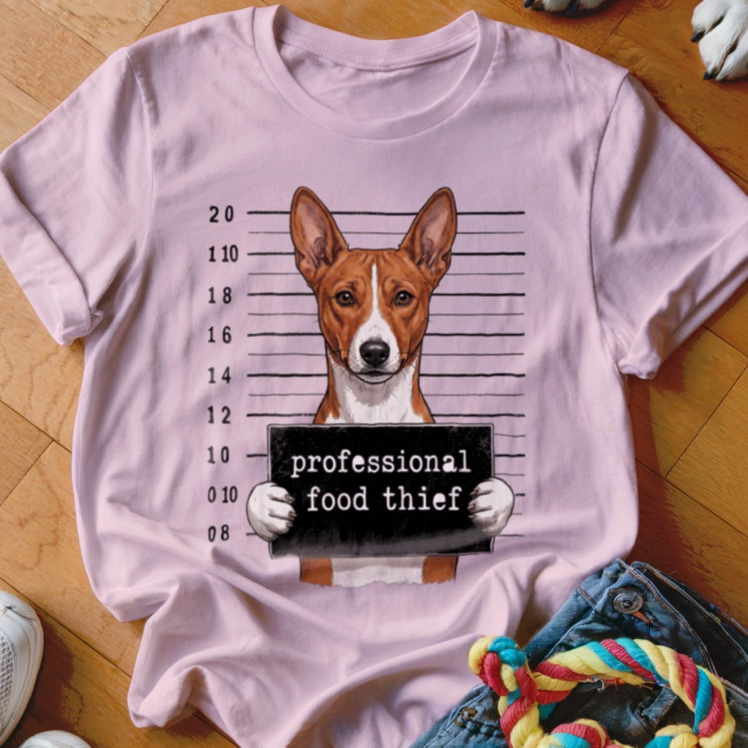 Dog mugshot with "professional food thief" sign on a pink t-shirt.
