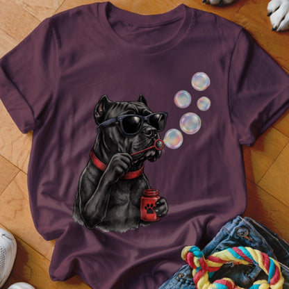 A plum-colored t-shirt displays an illustration of a black dog wearing sunglasses, blowing bubbles.
