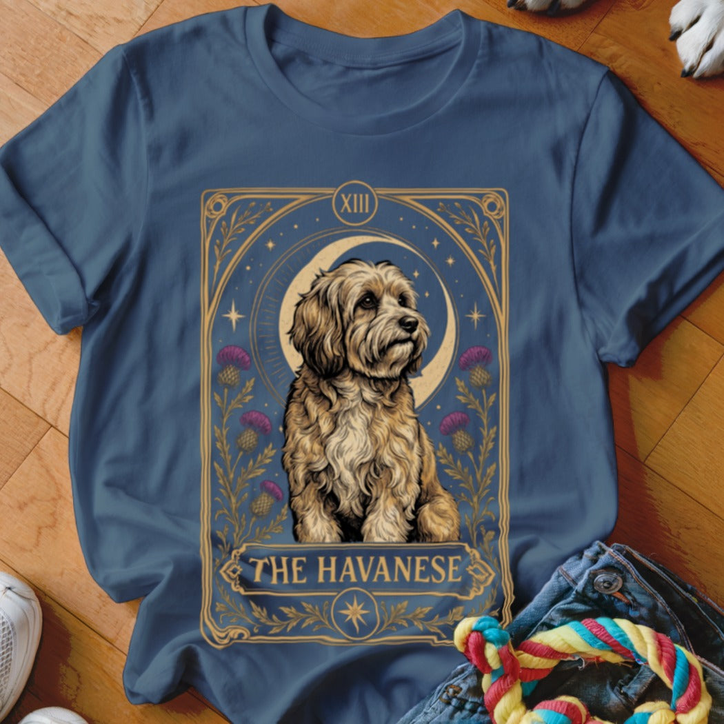A blue t-shirt featuring a tarot card style graphic of a Havanese dog with purple flowers.